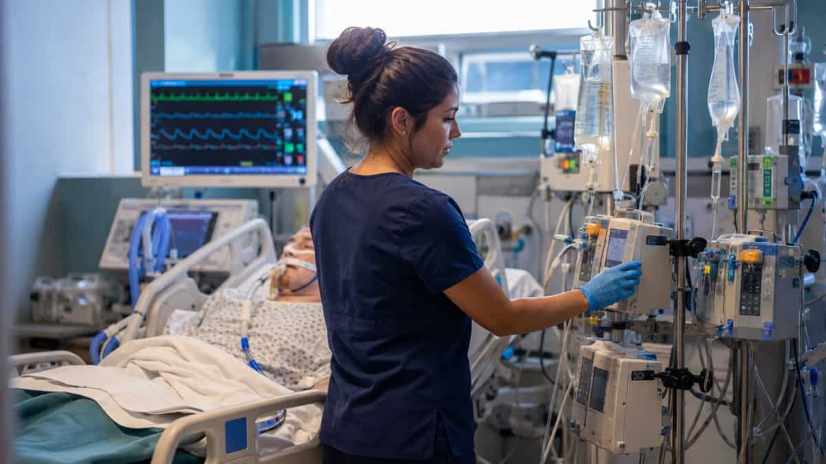 ICU nurse adjusting IV infusion pumps at a patient bedside, the critical care experience Cedar Crest College requires for CRNA program admission