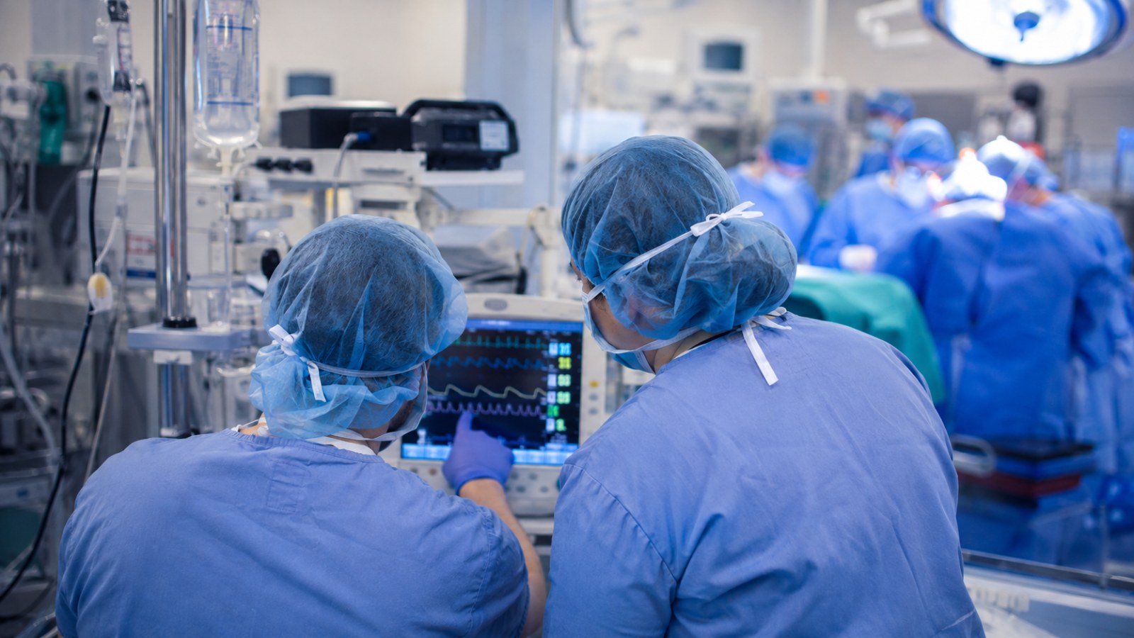 CRNA and student nurse anesthetist reviewing a patient monitor during a cardiac surgery case, representing the high case volume at the UPMC Hamot School of Anesthesia/Gannon University CRNA program in Erie