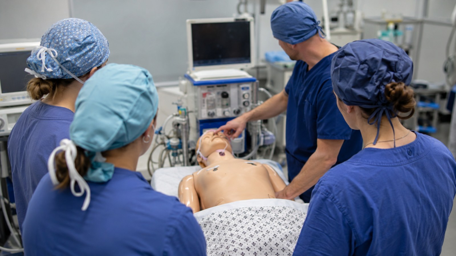 Small cohort of nurse anesthesia students around a high-fidelity simulation manikin with an instructor, representing the York College of Pennsylvania/WellSpan Health CRNA program